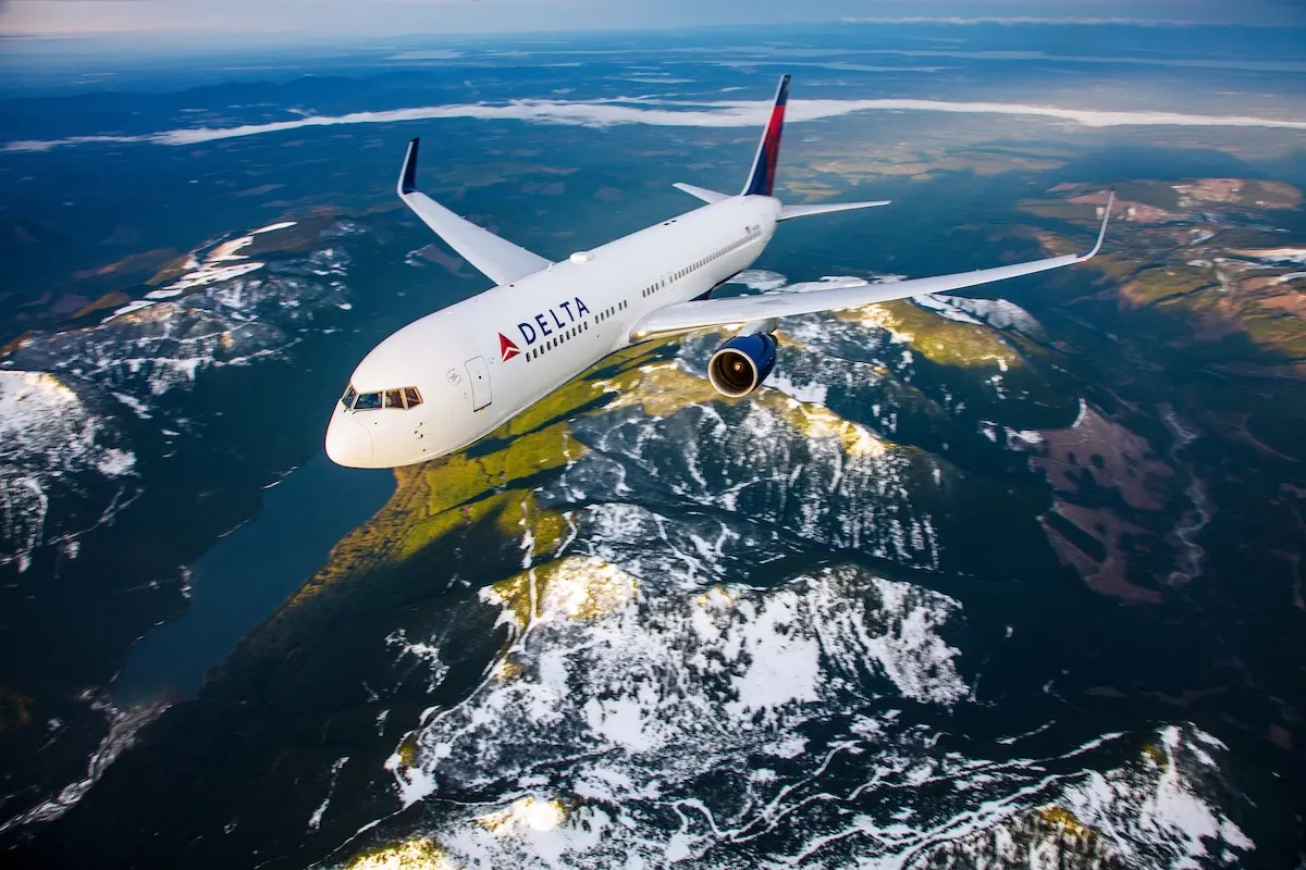 Delta airplane flying above a coastal landscape.