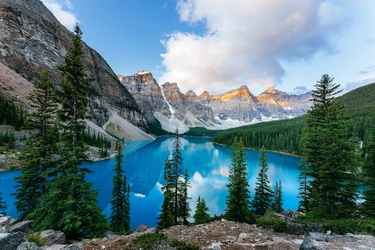 Clear blue mountain lake surrounded by trees and rocky peaks. 