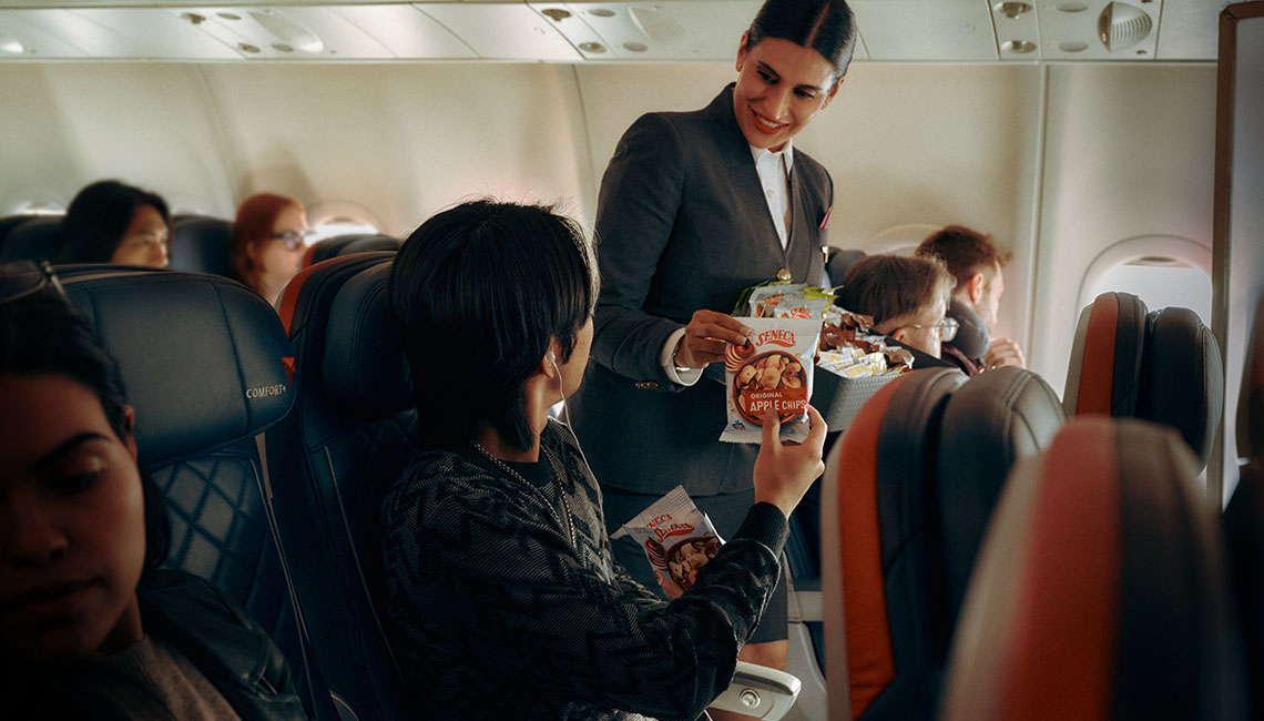 正在向达美优悦经济舱的乘客提供Seneca苹果薯片的飞机乘务员