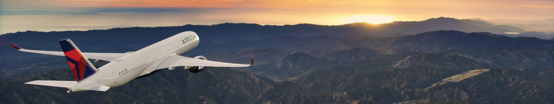 Delta Airbus airplane flying over mountains into sunset