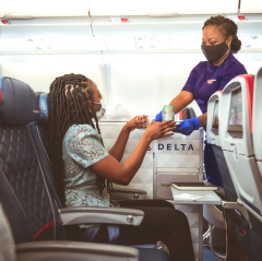 Steward/stewardess die snacks overhandigt aan passagier
