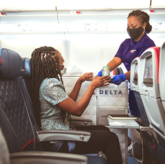 Flight attendant handing snacks to passenger