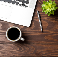 Coffee cup next to a computer and pencil