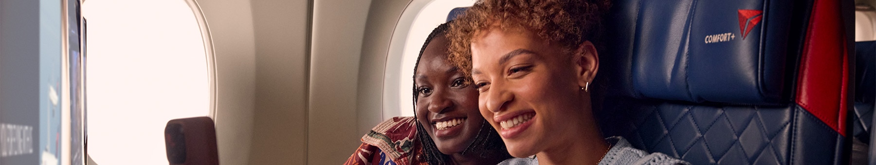 Two friends taking a selfie while seated in Delta Comfort.