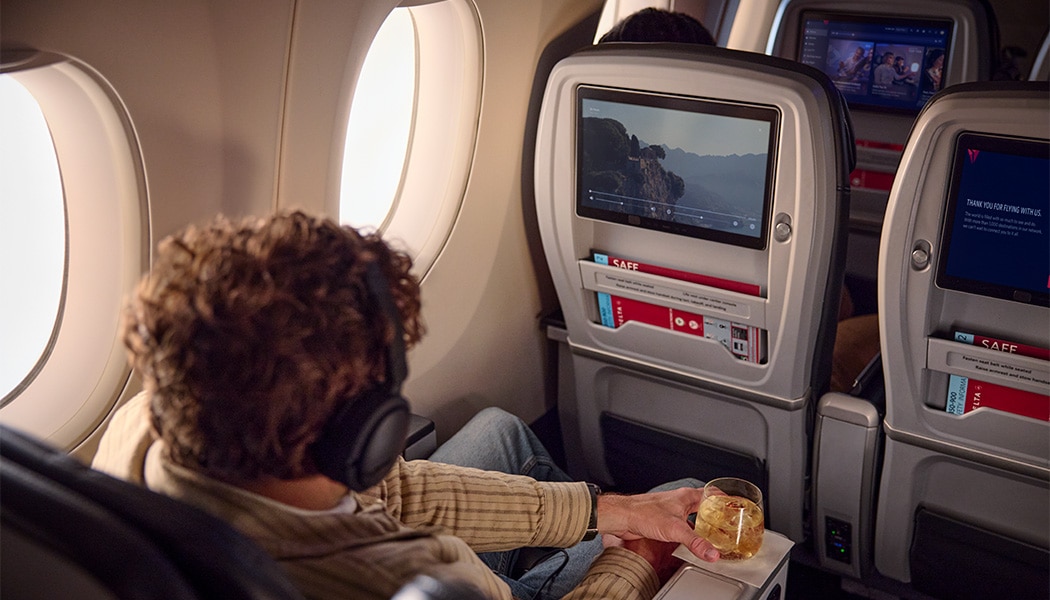 Man with headphones watching a movie on seatback screen.