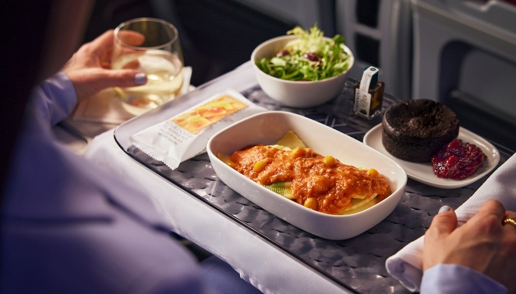 上質な食器に盛られた前菜、メインディッシュ、デザート、ワインを含むデルタ・プレミアムセレクトでのお食事のサービスの例