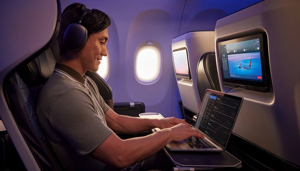 Man using laptop in First Class while connected to Delta Sync Fast, Free Wi-Fi