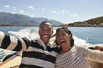 Two people taking selfie on boat, highlighting Delta SkyMiles travel rewards.