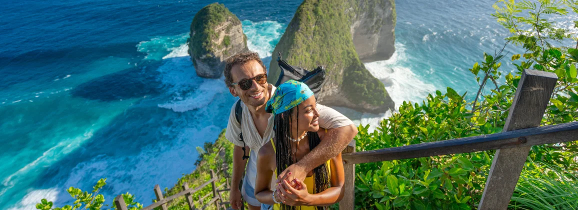 Couple overlooking tropical cliffs and ocean, highlighting Delta SkyMiles travel rewards.