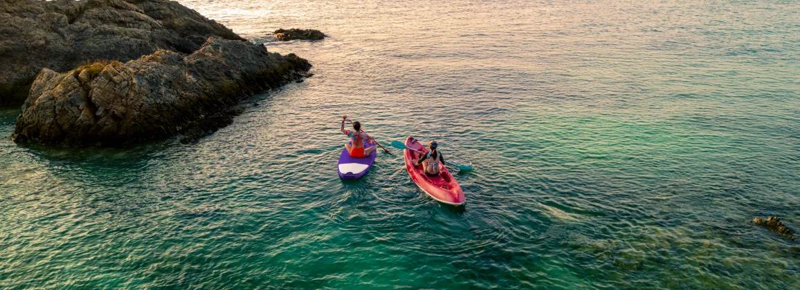 Two people kayaking near rocky shore, representing Delta SkyMiles travel experiences.