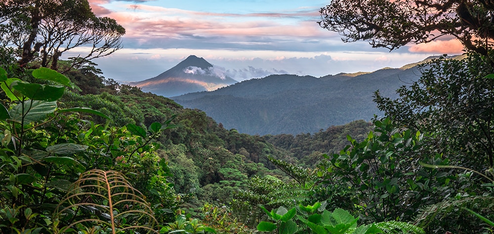 Lush rainforest and mountain view in Maui layered with green valleys and clouds at sunrise. 
