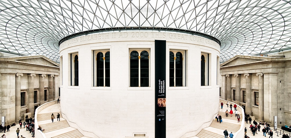 Interior of the British Museum Great Court featuring the historic Reading Room and modern glass ceiling. 