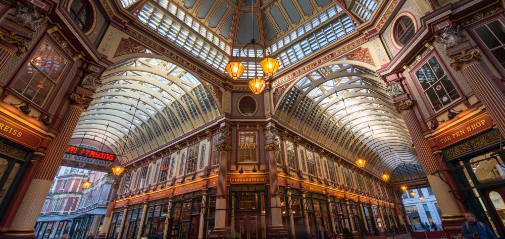 Leadenhall Market interior in London featuring Victorian ironwork, glass roof, and shops. 