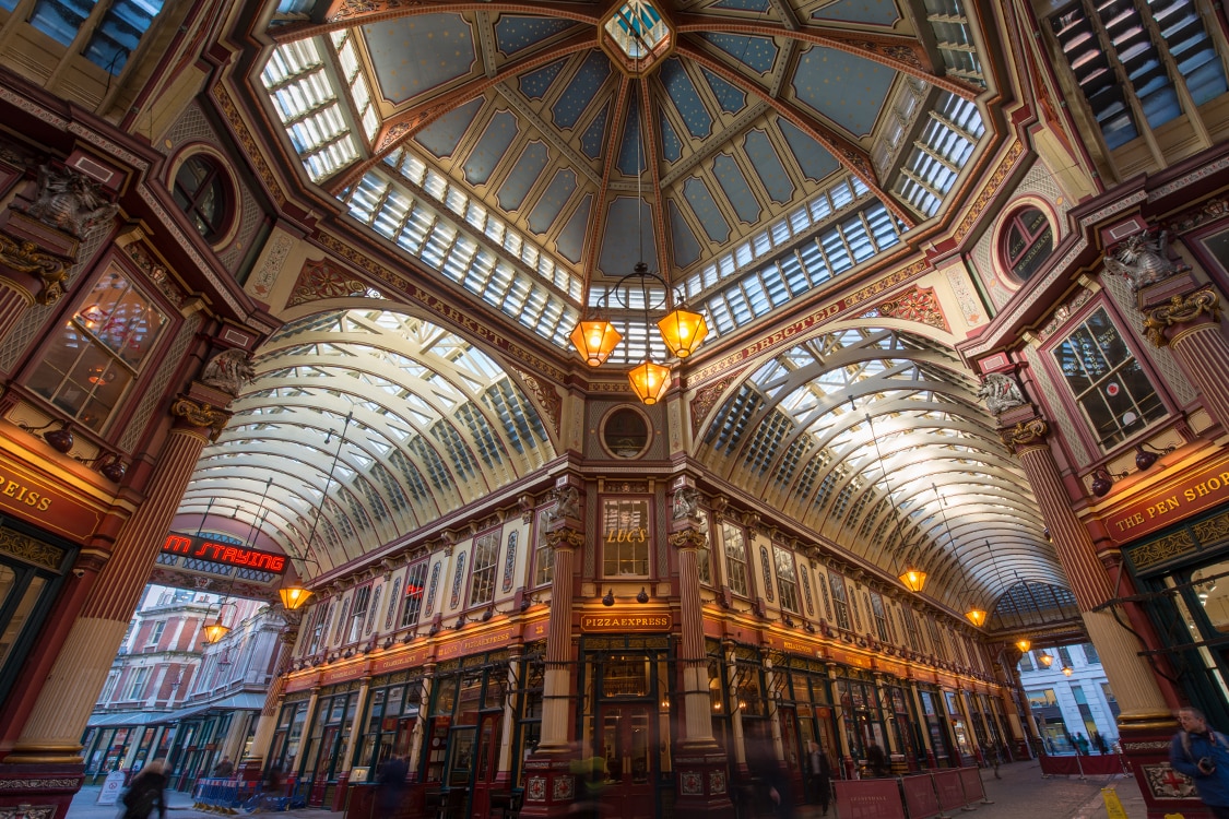 Leadenhall Market interior in London featuring Victorian ironwork, glass roof, and shops. 