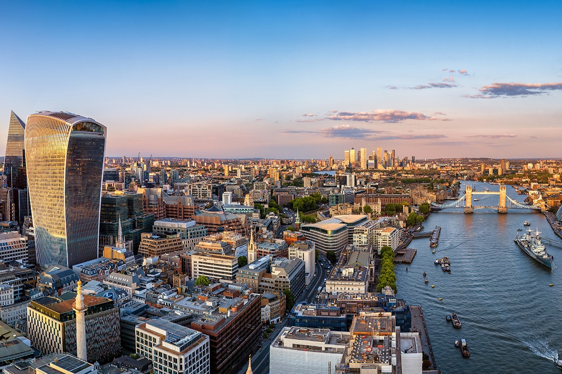 Aerial view of central London featuring the River Thames, Modern skyscrapers, and Tower Bridge. 