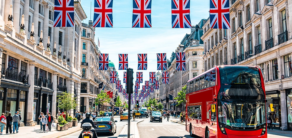 Regent Street in London decorated with Union Jack flags and double decker bus on a sunny day. 