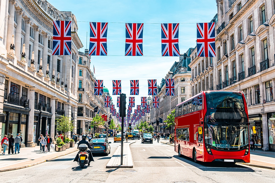 Regent Street in London decorated with Union Jack flags and double decker bus on a sunny day. 
