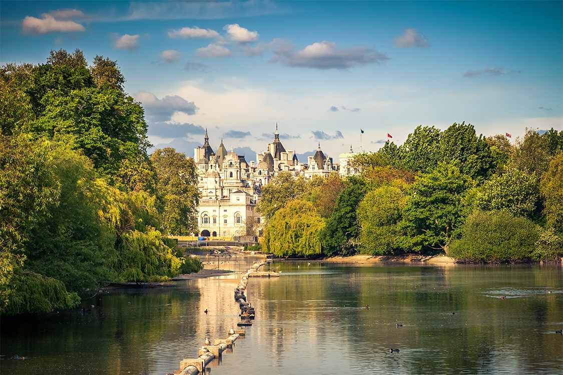 View across St James's Park toward Whitehall and Horse Guards buildings surrouned by greenery. 