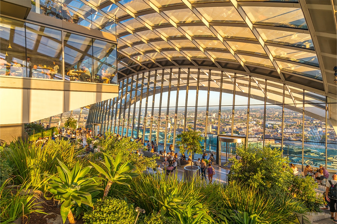 Sky Garden in London with indoor greenery and panoramic city views through a glass atrium during sunset. 