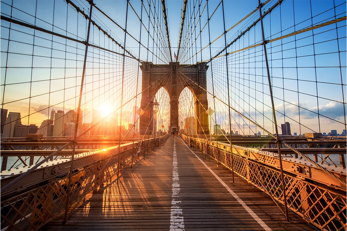 Sunrise view from the Brooklyn Bridge pedestrian walkway with New York City Skyline in the distance. 