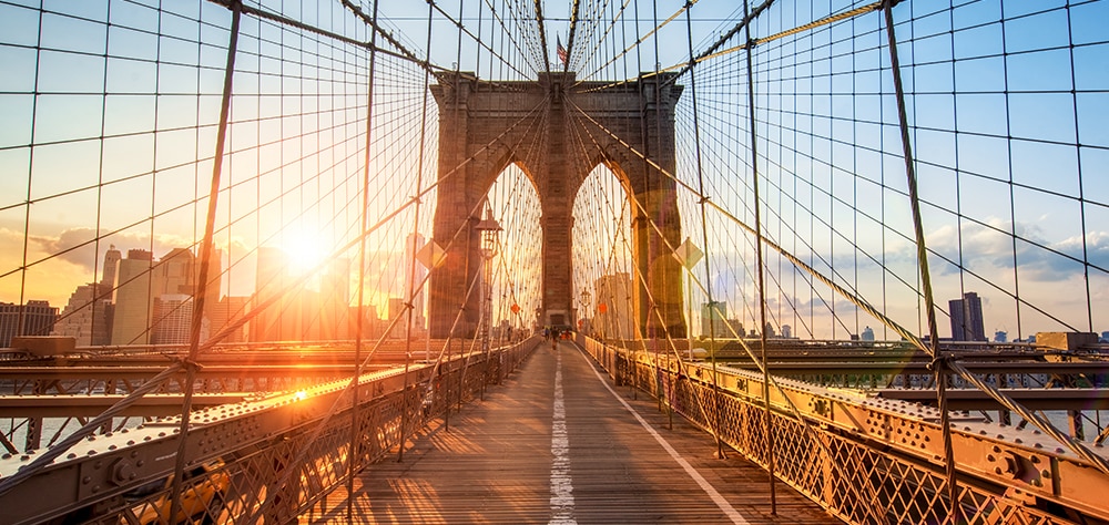 Sunrise view from the Brooklyn Bridge pedestrian walkway with New York City Skyline in the distance. 