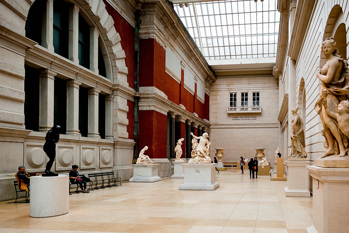 The Met Museum European sculpture court featuring classical statues and visitors.