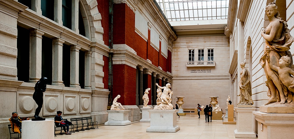 The Met Museum European sculpture court featuring classical statues and visitors.