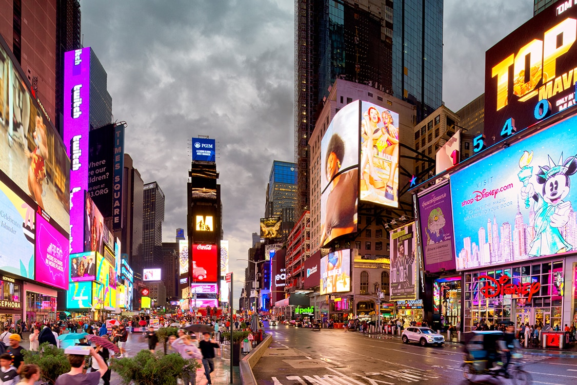 Times Square at night with bright digital billboards, crowds, and traffic in New York City. 