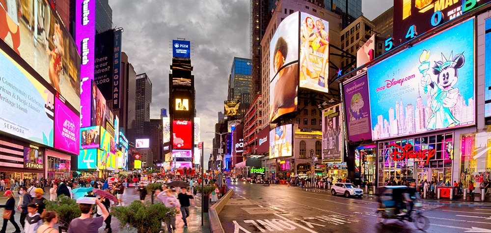 Times Square at night with bright digital billboards, crowds, and traffic in New York City. 