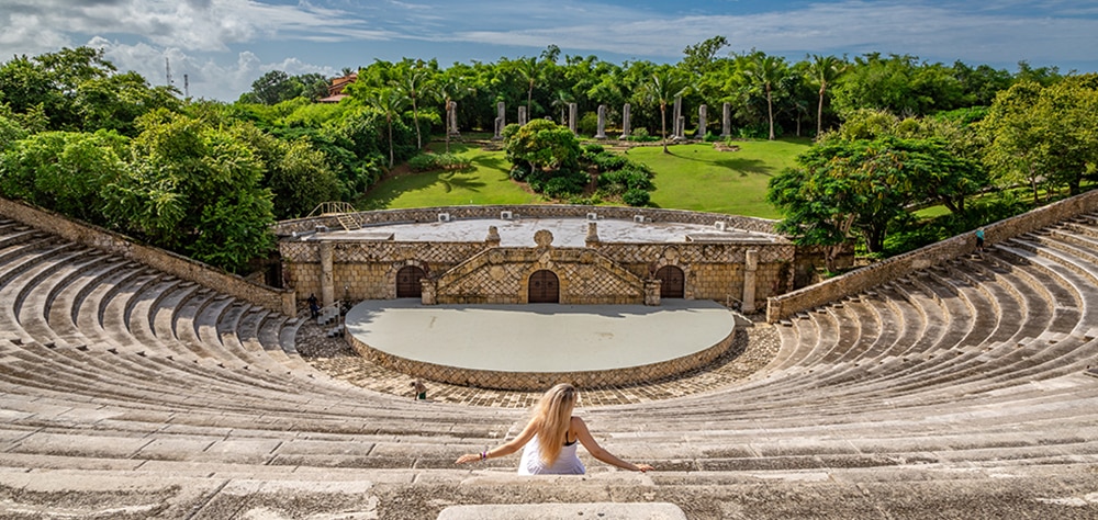 Woman sitting in stone ampitheater surrounded by lush gardens in the Dominican Republic.