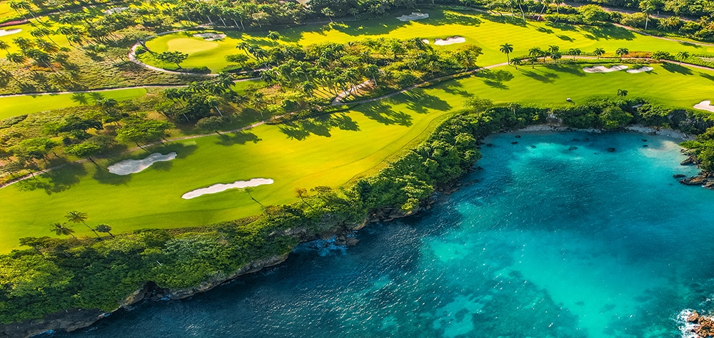 Aerial view of gold course with lush green golf courses with turquoise blue waters. 