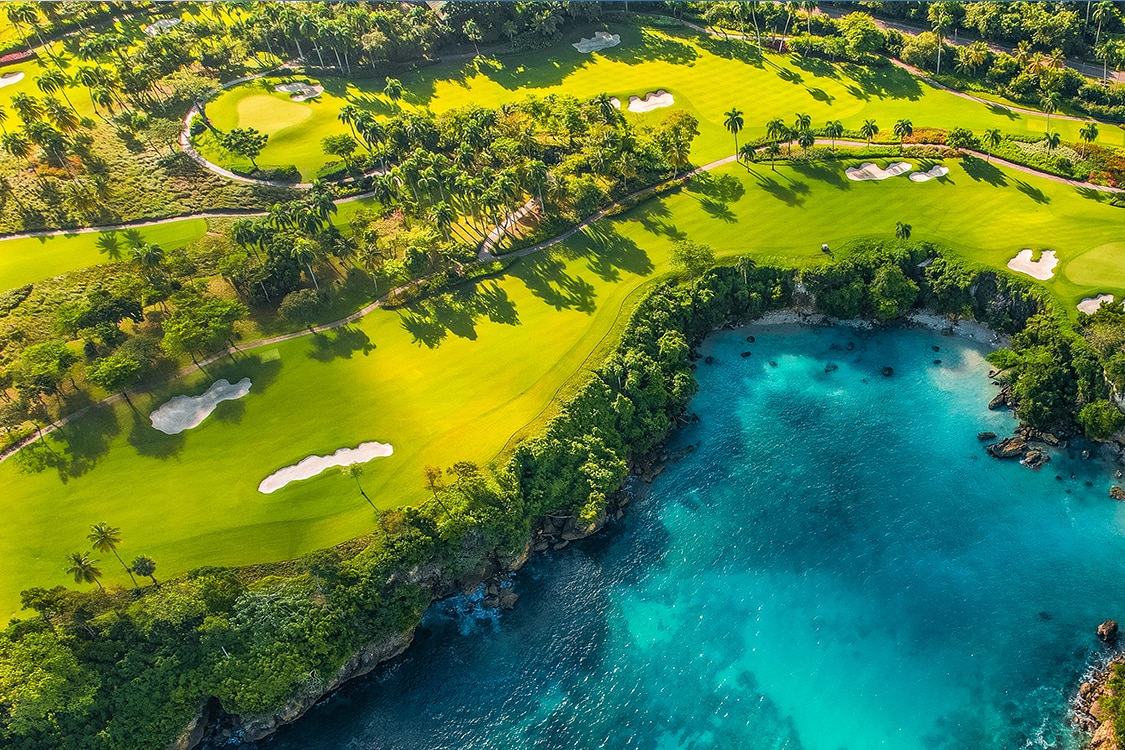 Aerial view of gold course with lush green golf courses with turquoise blue waters. 