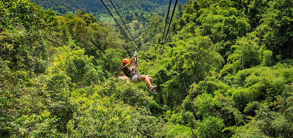 Traveler ziplining through lush green jungles in Punta Cana. 