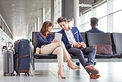 Young man and woman waiting for flight at airport terminal